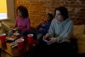 Group of diverse teens playing video games in a cozy indoor setting.