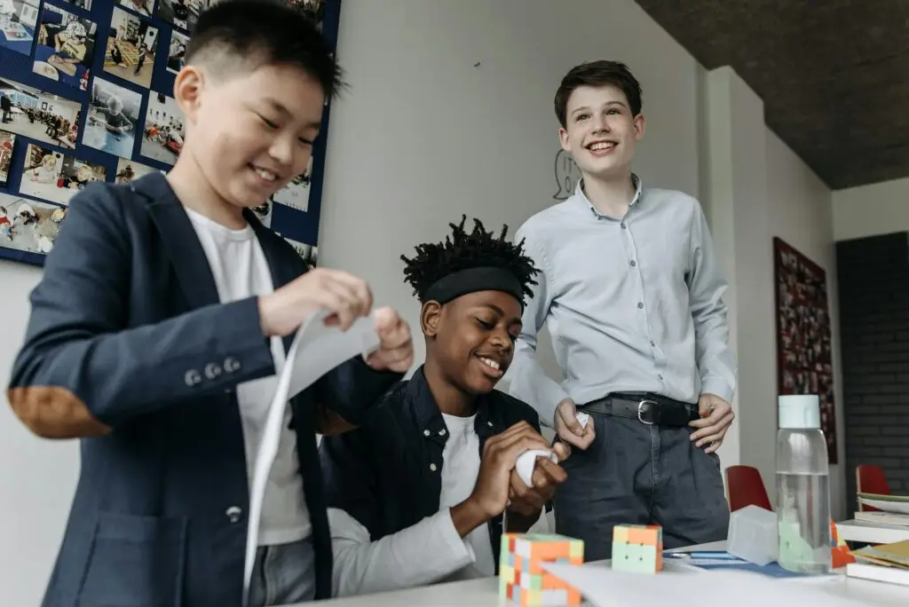Three smiling teens enjoying a creative activity indoors, showcasing friendship and diversity.